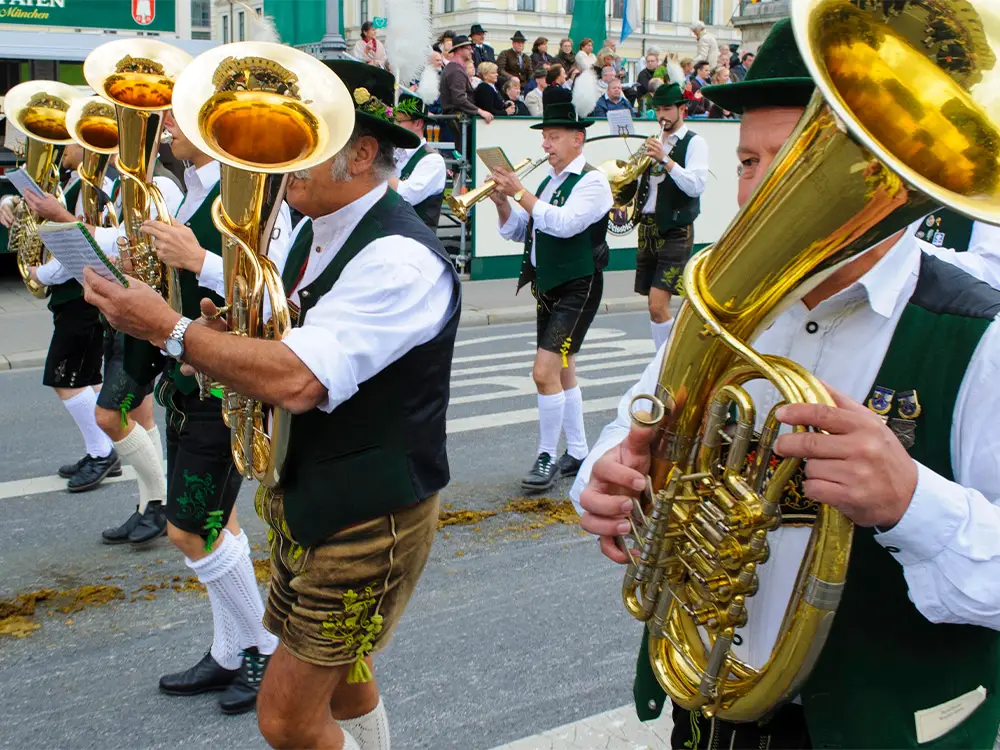 Traditional Bavarian brass band marching in lederhosen during an Oktoberfest parade in Germany.