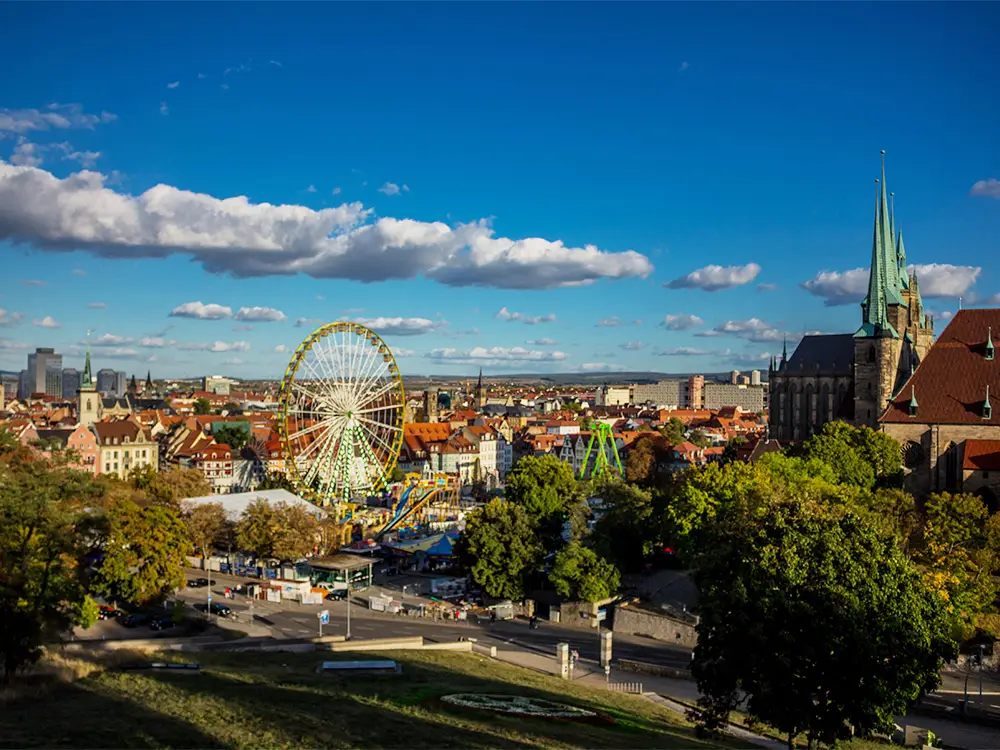Ferris wheel and rides at Erfurt Oktoberfest with panoramic view of the old town and cathedral in Thuringia, Germany.