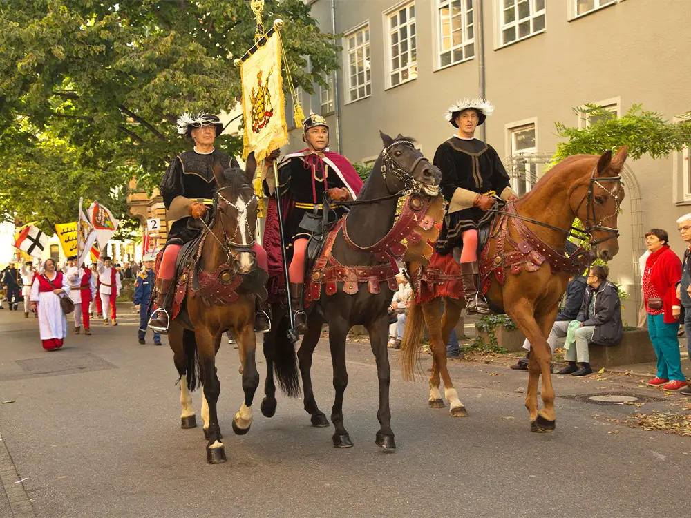 Costumed riders on horseback in a traditional German parade during Cannstatter Volksfest in Stuttgart.