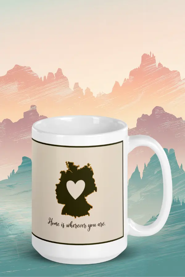Home is wherever you are mug Sentimental German mug with a silhouette of Germany with a heart in the center. The text reads, "Home is wherever you are." The background is a painted landscape of mountains.