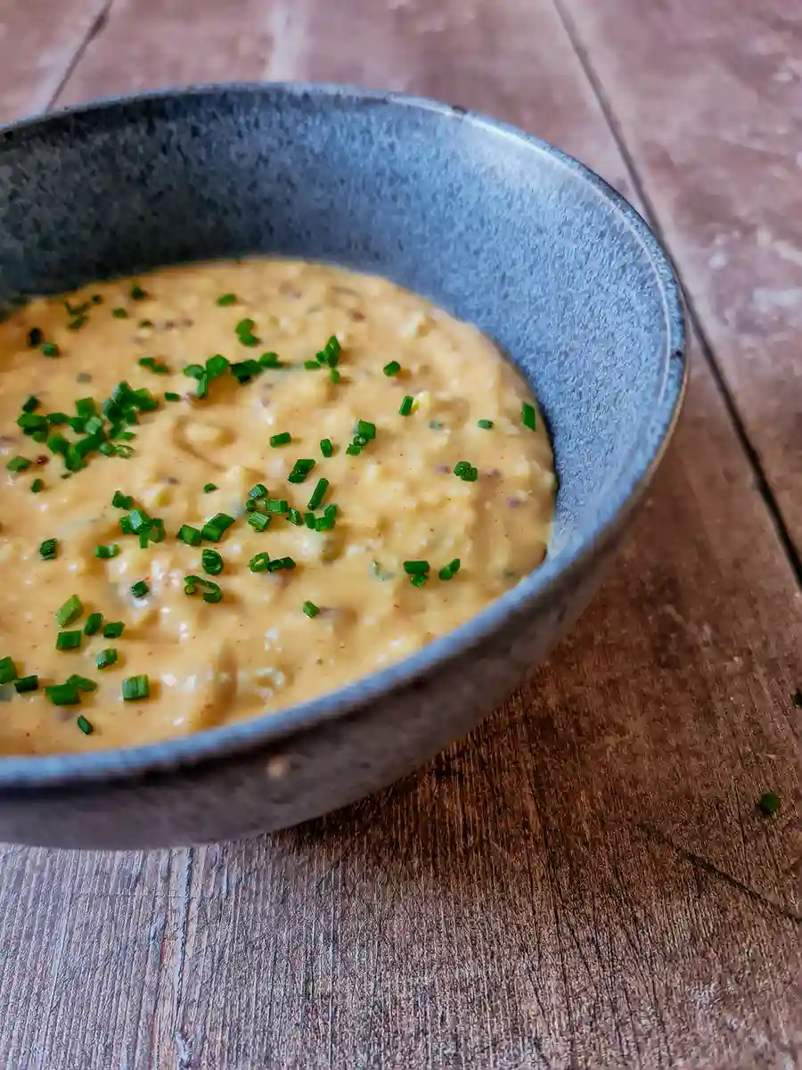 Finished bowl of Obatzda Bavarian-style Obatzda beer cheese dip served in a bowl with a Warsteiner beer bottle in the background.