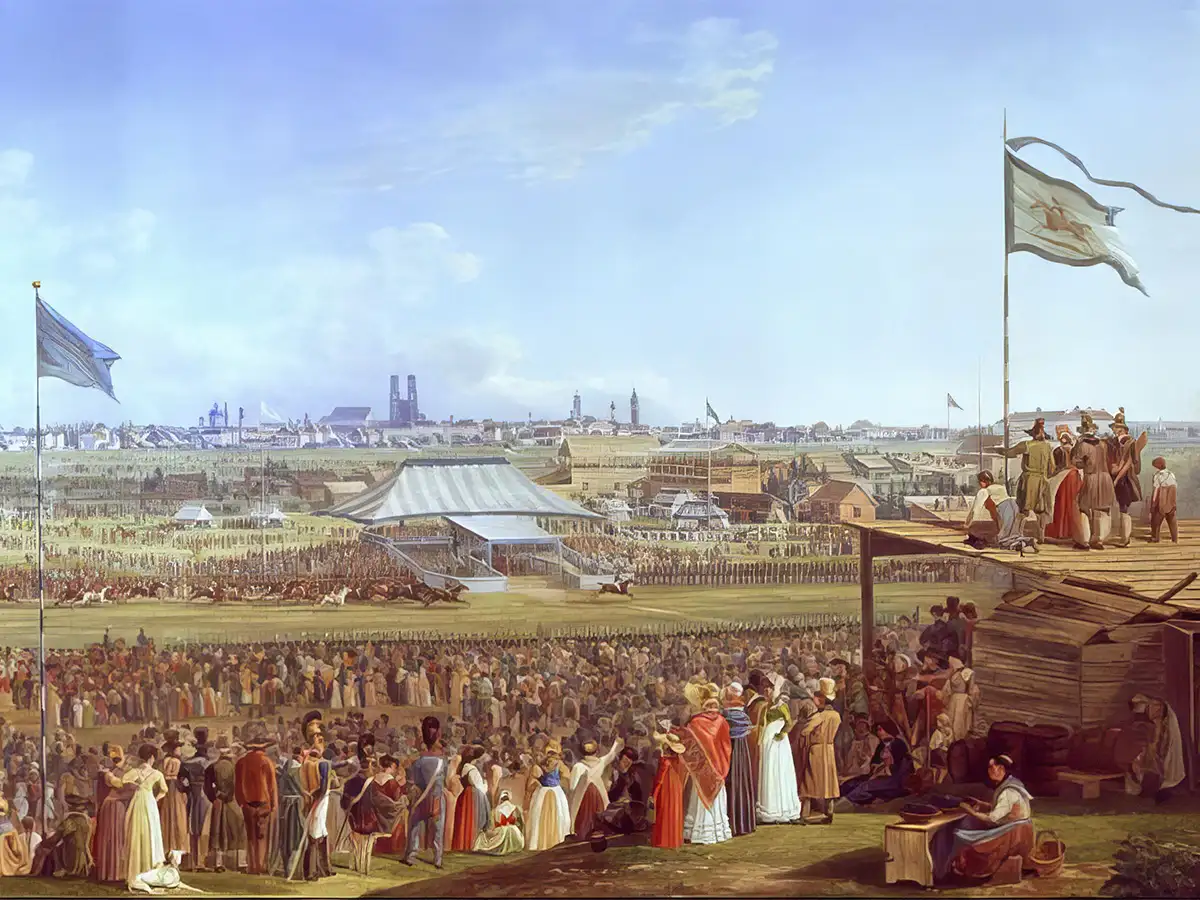 Historical painting showing a large outdoor festival in 1823 Munich with tents, flags, and crowds dressed in 19th-century clothing.