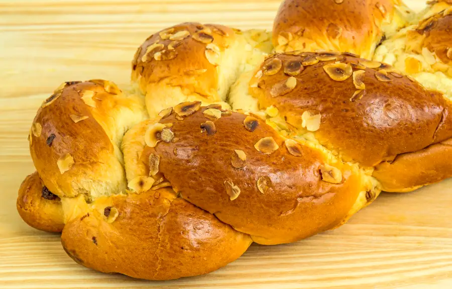 Golden braided Hefezopf German Easter bread topped with toasted almond flakes and raisins, a traditional Easter Sunday centerpiece
