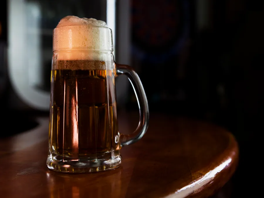 Foamy mug of dark beer on a wooden table, the Bavarian Starkbier tradition linked to Lent fasting.