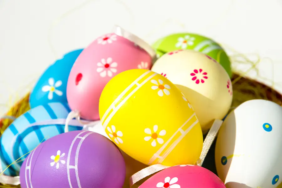 A collection of brightly colored, decorated Easter eggs with floral and striped patterns, arranged together.