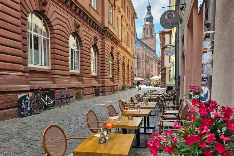 Café tables on a cobblestone street in Heidelberg for a German town coloring page for kids