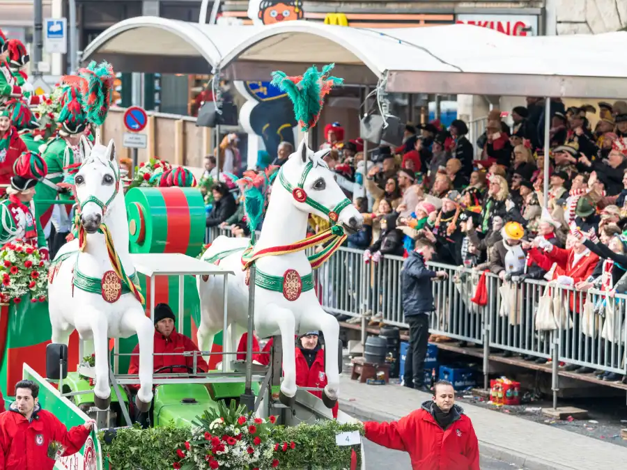 Cologne Karneval parade float with white horse figures and crowds watching from grandstands in Köln