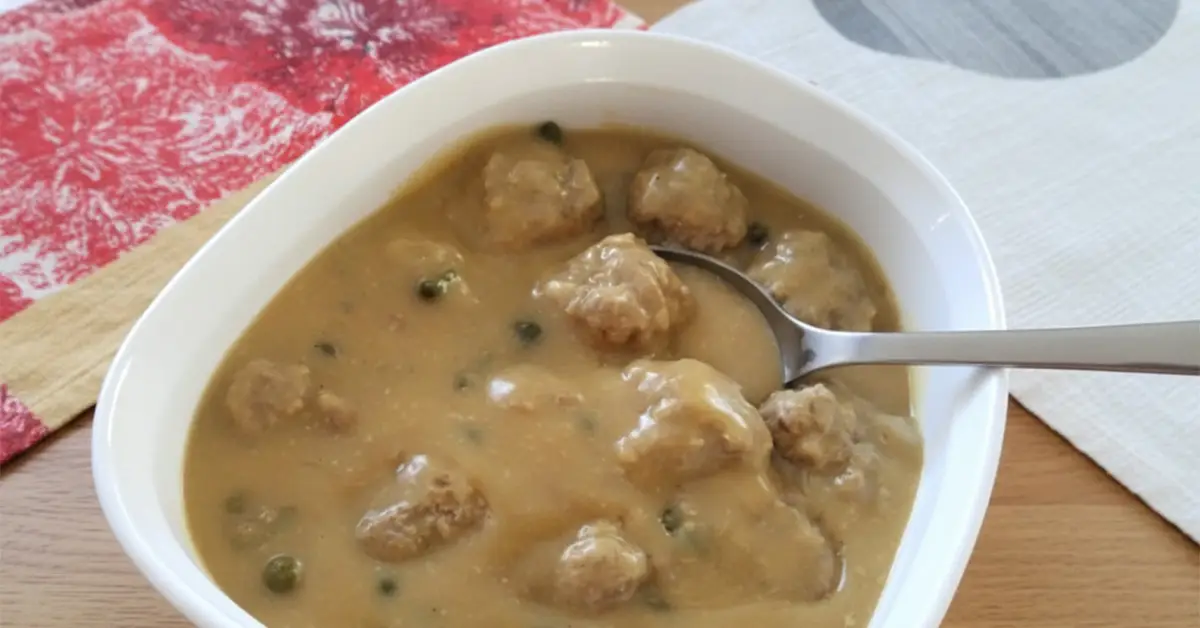 Traditional Königsberger Klopse German meatballs served in creamy white sauce with capers in a white bowl on a table.