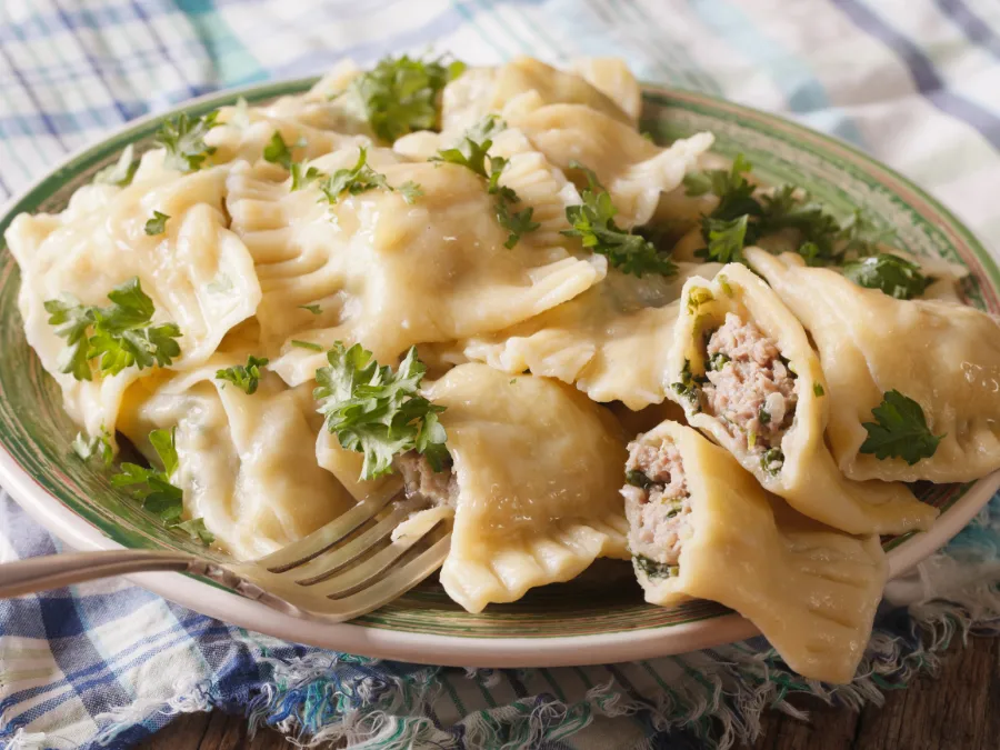 Plate of maultaschen dumplings topped with parsley, one cut open to show filling, a classic Lent loophole in Germany.