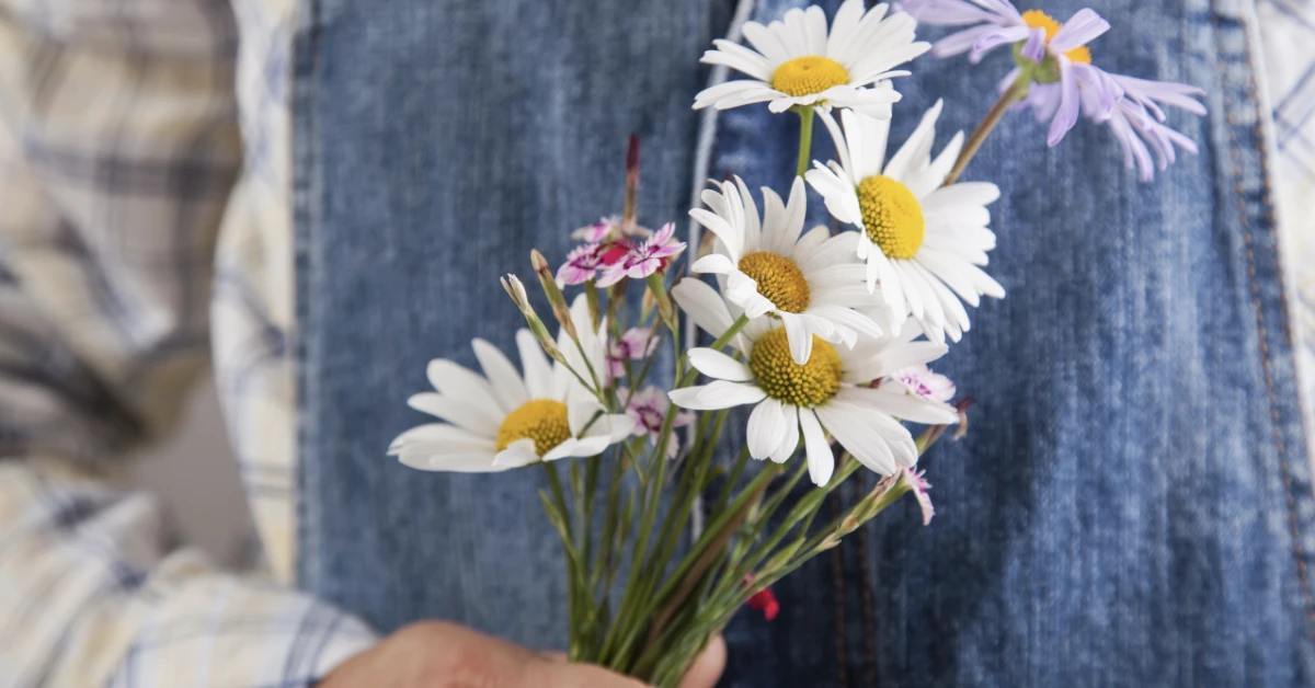 Child holding daisies behind their back for Muttertag