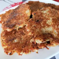 A plate stacked with crispy golden-brown potato pancakes, also known as Reibekuchen or Kartoffelpuffer, freshly pan-fried and ready to serve.