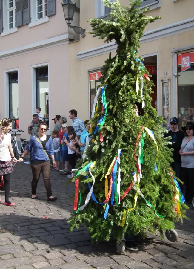 Evergreen “Butzen” summer figure with ribbons at Sommertagszug, representing returning life and spring.