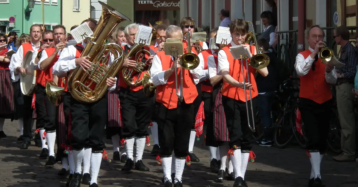 Brass band leads a Sommertagszug spring parade in Germany, musicians marching in traditional dress.