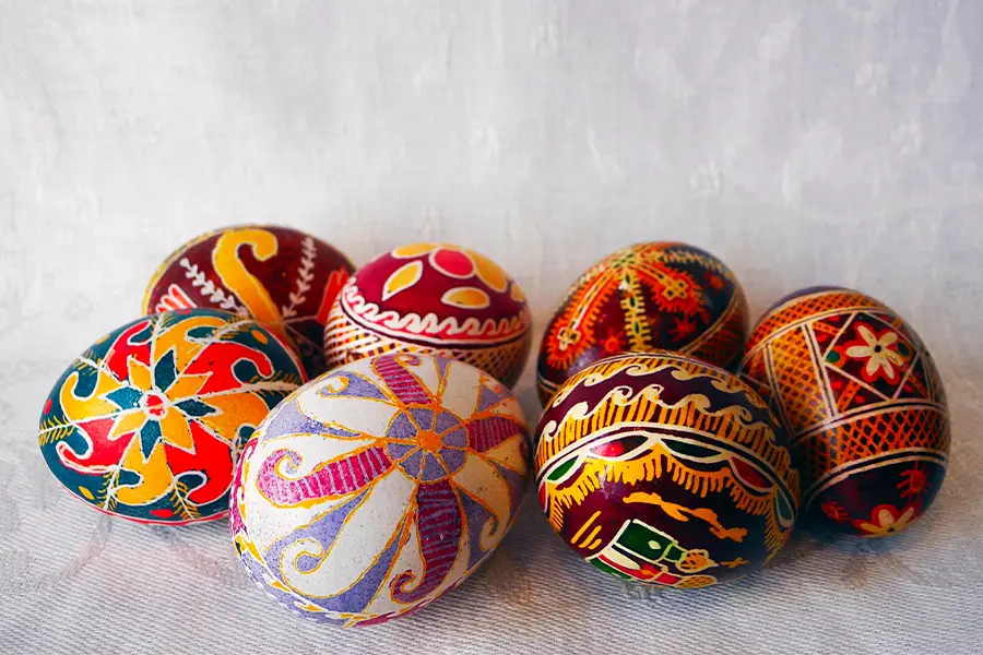 Seven intricately decorated eggs with colorful patterns placed on a light textured surface.