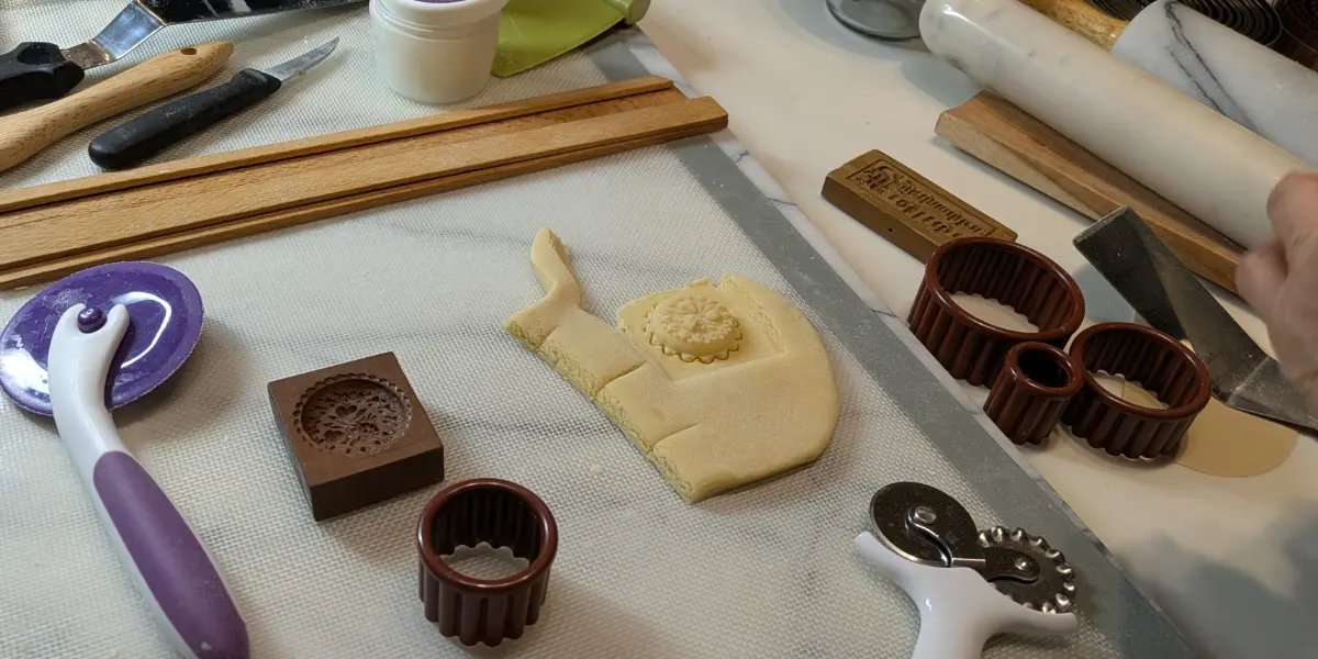 Springerle cookie dough prepared with traditional wooden molds and baking tools on a work surface.