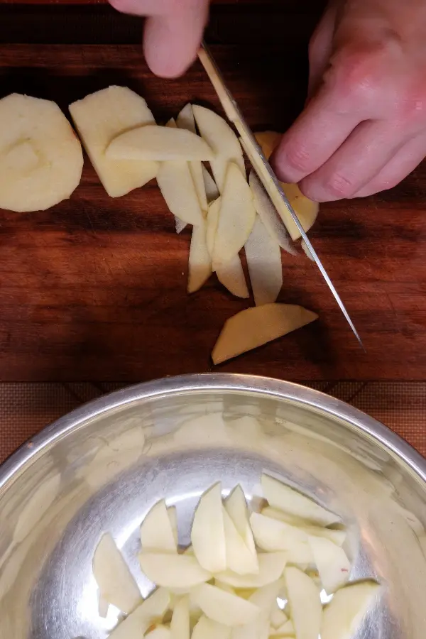 Apples being sliced on a chopping board.