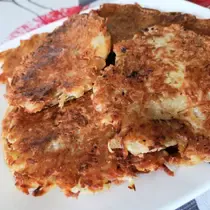 A plate stacked with crispy golden-brown potato pancakes, also known as Reibekuchen or Kartoffelpuffer, freshly pan-fried and ready to serve.